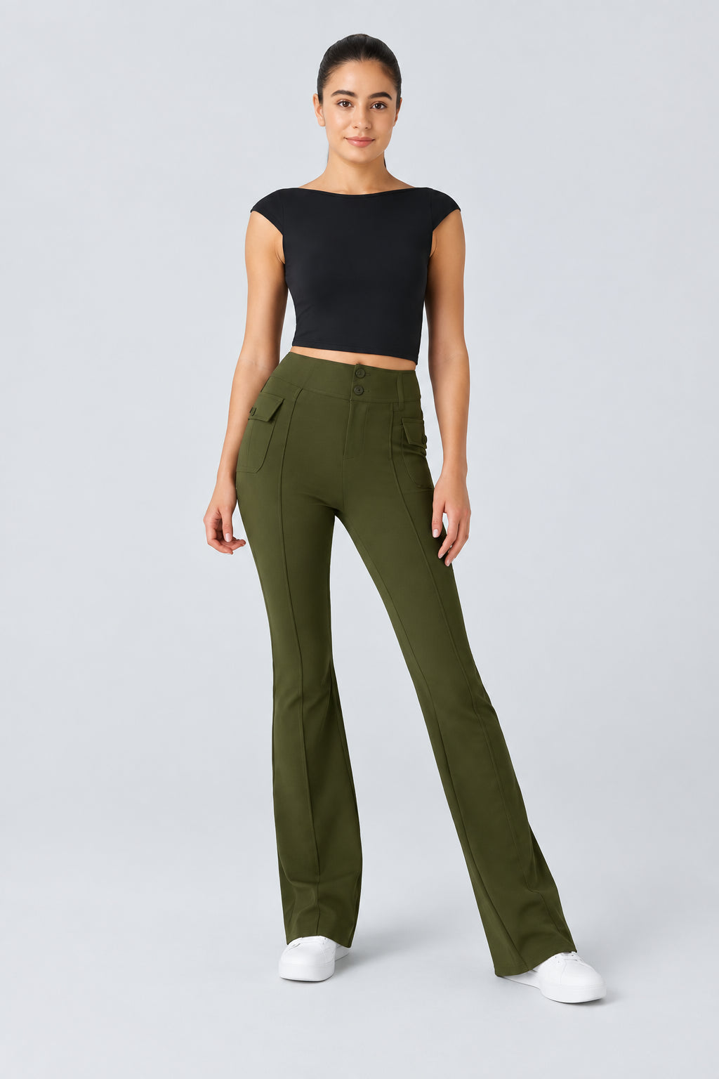 Woman wearing a black top and green pants on a light gray background