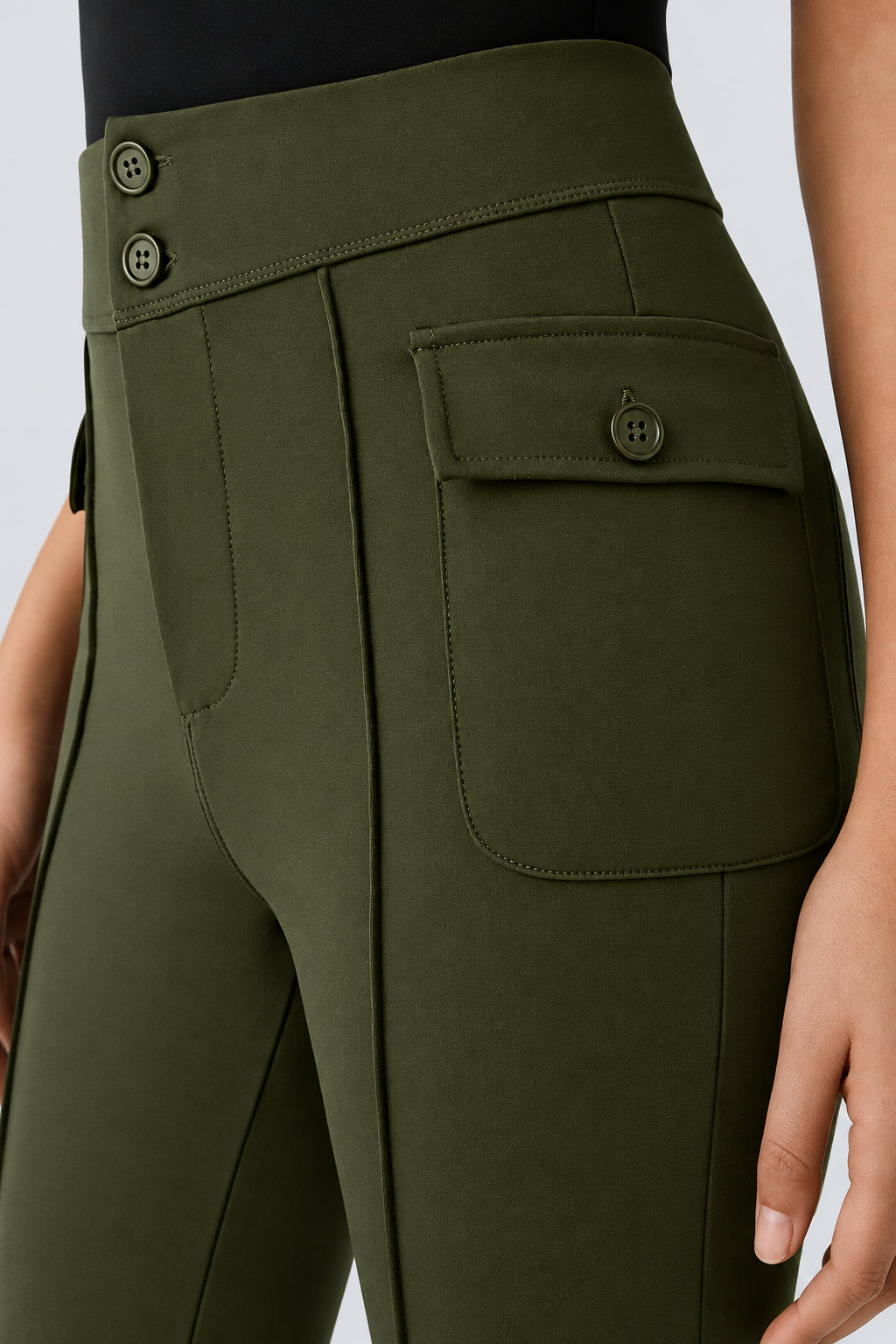 Close-up of olive green pants with button details on a light gray background